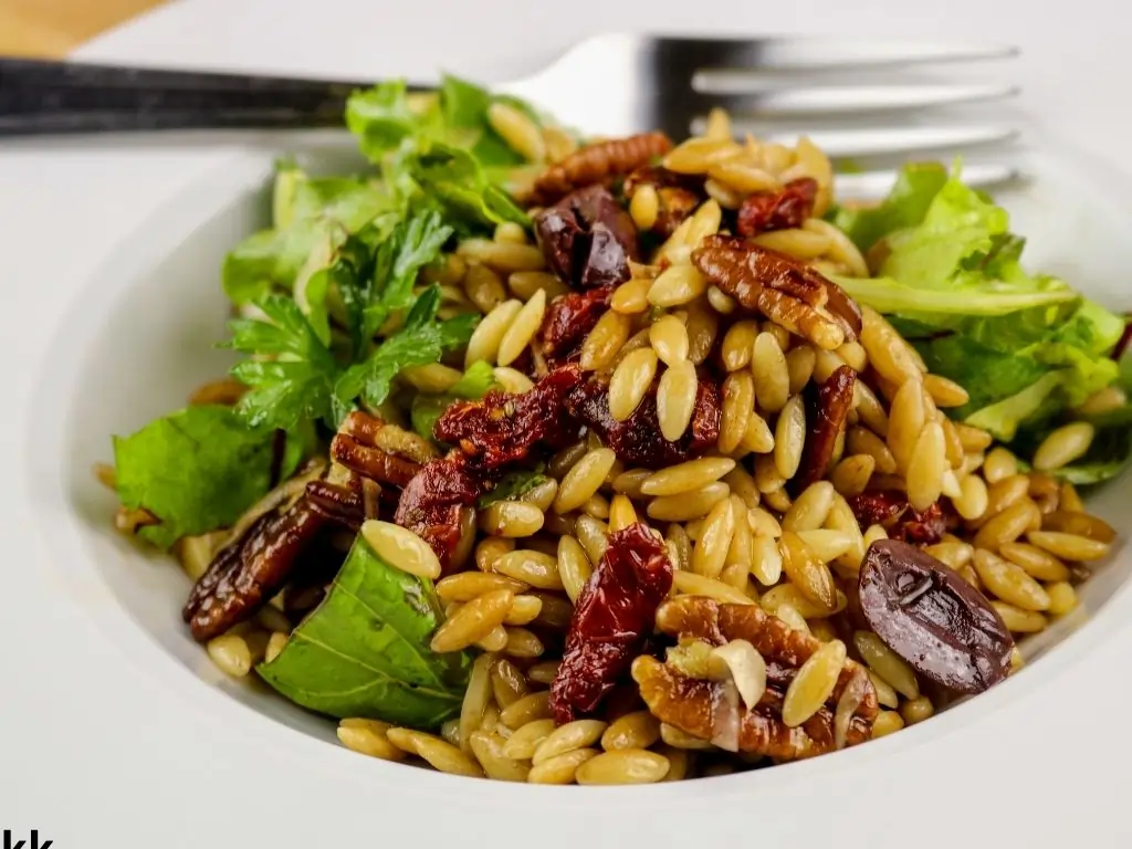 a freshly made summer vegan orzo salad, sun-dried tomatoes, fresh basil and parmesan cheese